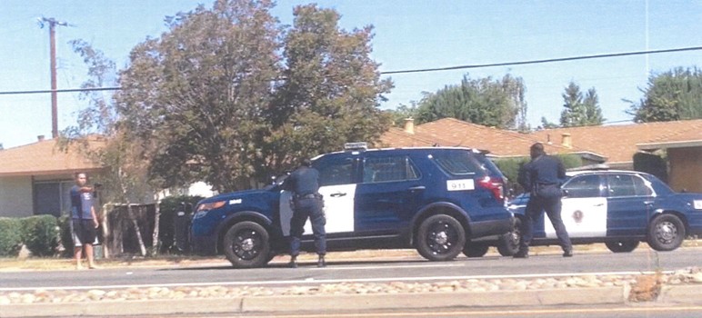 Police with weapons drawn and aimed at a girl holding a drill.