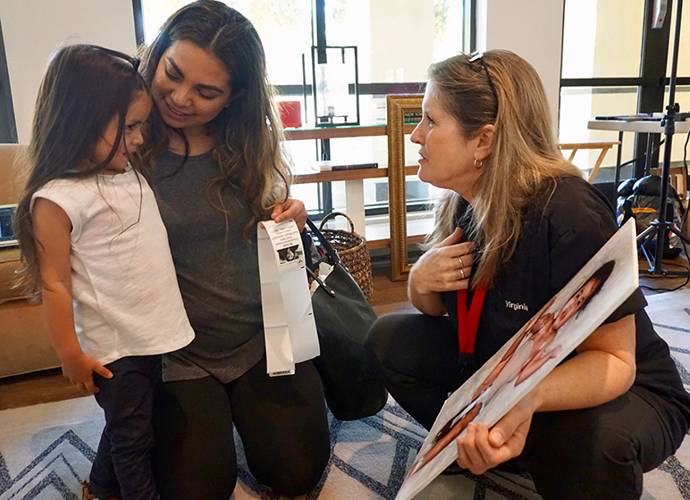 Virginia Becker (right) shows Gigi (left) a photo of her as a baby attached to an artificial heart. (Photo by Jennifer Wadsworth)