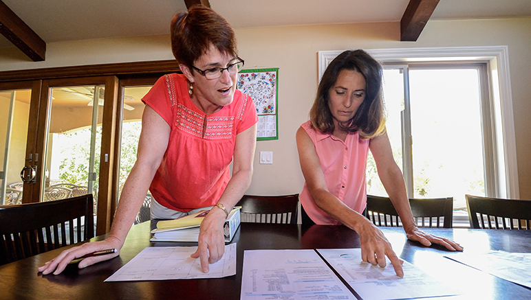 Ginny Hoerger (left) and Rita Benton pore over water bills and other records. (Photo by Greg Ramar)
