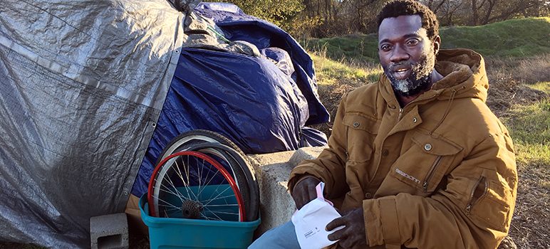 Sharwian Bobian sits outside his makeshift shelter.